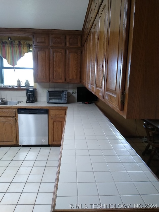 kitchen with backsplash, tile counters, and stainless steel dishwasher