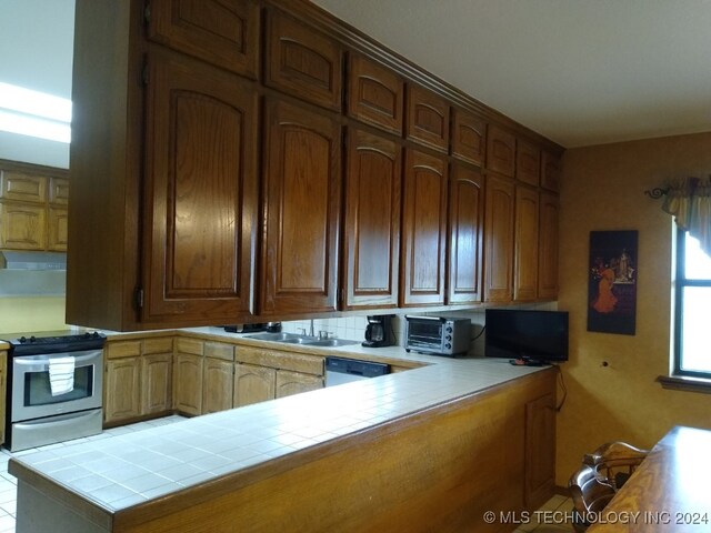 kitchen featuring tasteful backsplash, kitchen peninsula, white dishwasher, tile countertops, and stainless steel range with electric cooktop