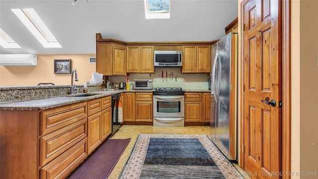 kitchen with stainless steel appliances, stone counters, a skylight, sink, and a wall mounted air conditioner