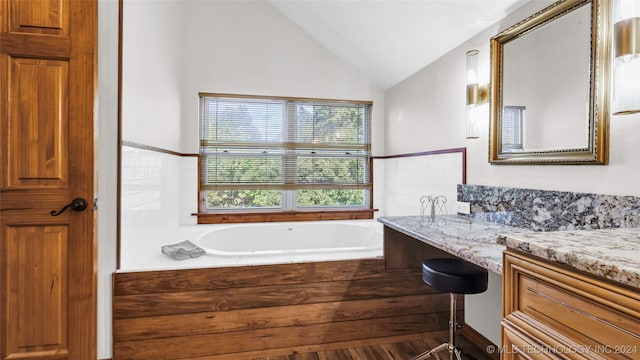 bathroom featuring vanity, lofted ceiling, hardwood / wood-style flooring, and a washtub