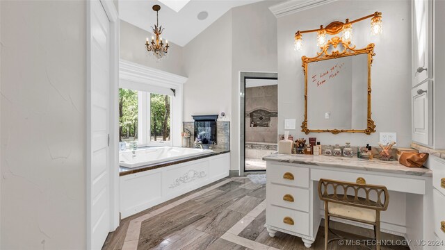 bathroom featuring a tub to relax in, vanity, an inviting chandelier, and high vaulted ceiling