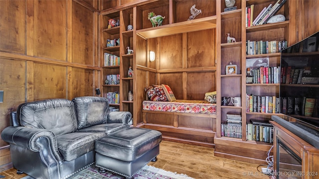 living area with wood walls and hardwood / wood-style floors