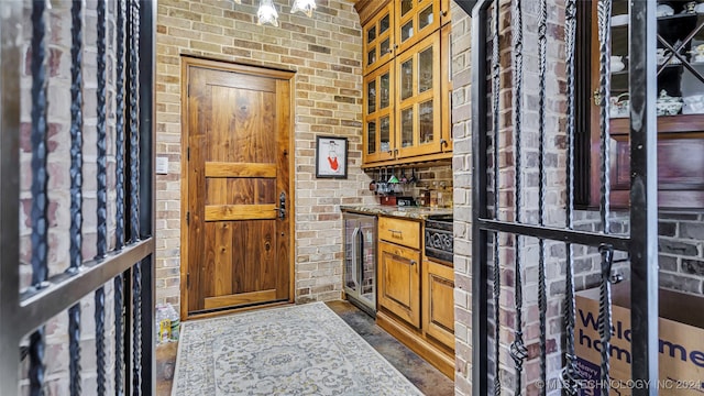 interior space featuring beverage cooler, brick wall, and stone counters