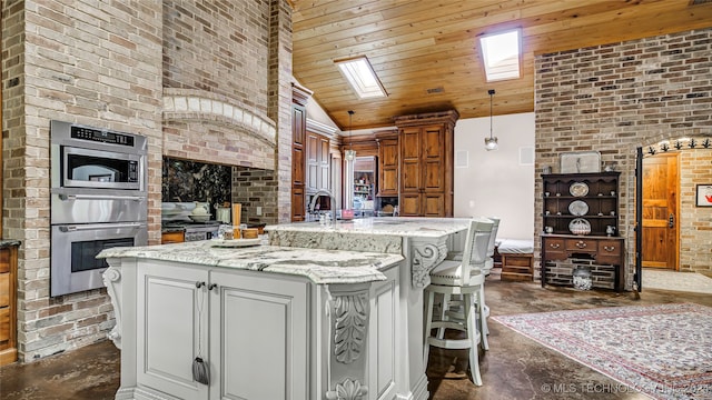 kitchen with pendant lighting, vaulted ceiling with skylight, a breakfast bar, wood ceiling, and a center island with sink