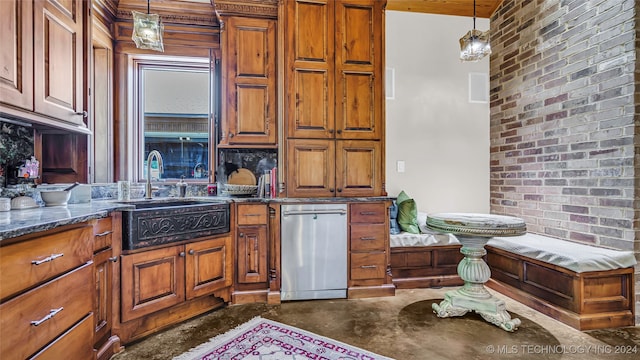 kitchen featuring brick wall, stainless steel dishwasher, sink, and decorative light fixtures