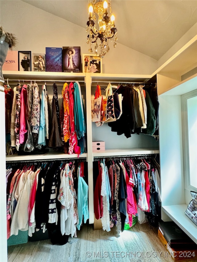 walk in closet with lofted ceiling, hardwood / wood-style floors, and a chandelier