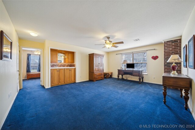 misc room featuring ceiling fan, a textured ceiling, and dark carpet