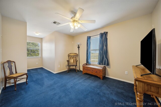 sitting room with dark colored carpet and ceiling fan