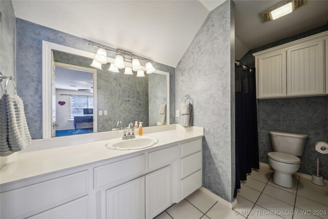 bathroom with vaulted ceiling, vanity, a shower with shower curtain, toilet, and tile patterned floors