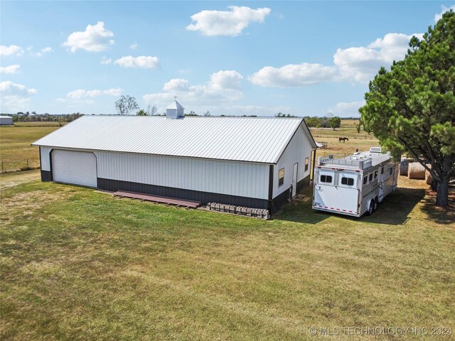 exterior space with a garage, a rural view, and a yard