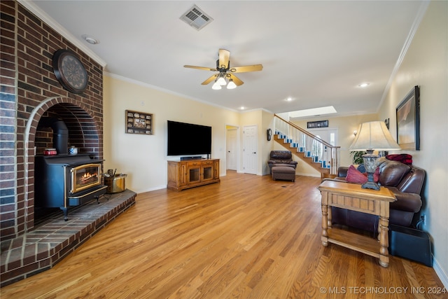 living room featuring crown molding, hardwood / wood-style floors, ceiling fan, and a wood stove