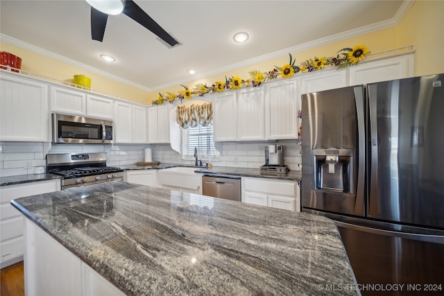 kitchen featuring sink, white cabinetry, stainless steel appliances, dark stone countertops, and decorative backsplash