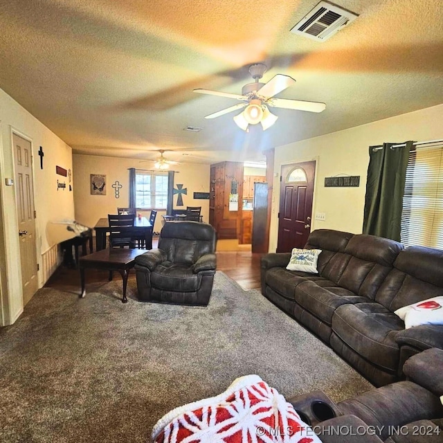 carpeted living room with ceiling fan and a textured ceiling