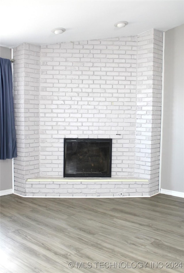 interior details with wood-type flooring and a brick fireplace