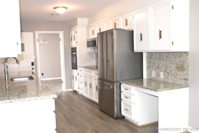 kitchen featuring sink, light stone counters, black appliances, backsplash, and white cabinets