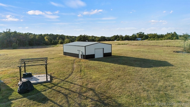 view of yard featuring a rural view, a garage, and an outbuilding