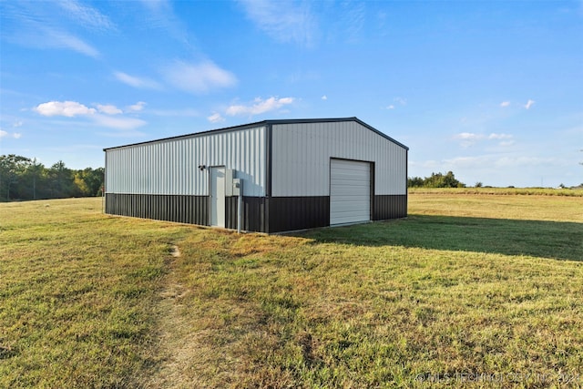 view of outbuilding featuring a lawn, a garage, and a rural view