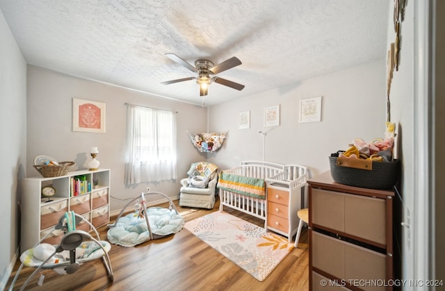 bedroom with ceiling fan, hardwood / wood-style flooring, and a textured ceiling