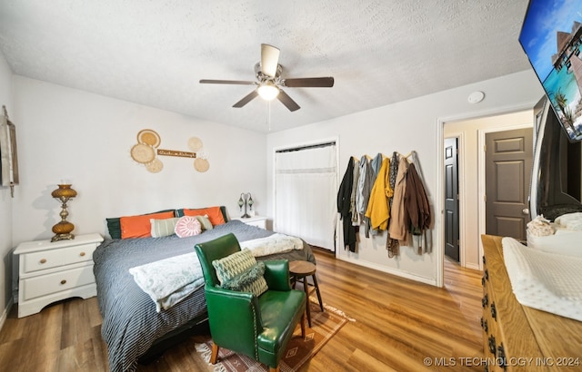 bedroom with wood-type flooring, a textured ceiling, a closet, and ceiling fan