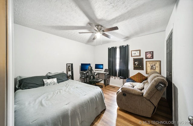 bedroom with ceiling fan, a textured ceiling, and light hardwood / wood-style floors