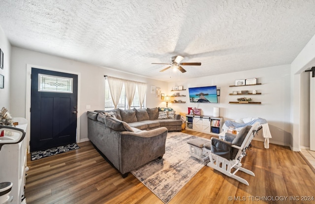 living room with ceiling fan, dark wood-type flooring, and a textured ceiling