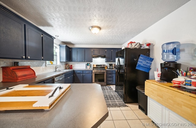 kitchen featuring appliances with stainless steel finishes, decorative backsplash, light tile patterned floors, a textured ceiling, and sink