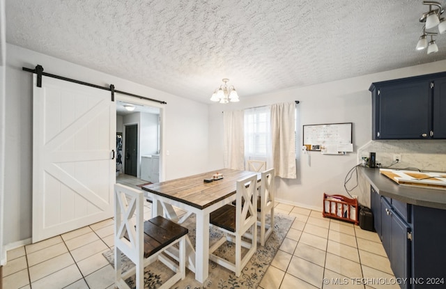 dining area with a barn door, a textured ceiling, an inviting chandelier, and light tile patterned floors