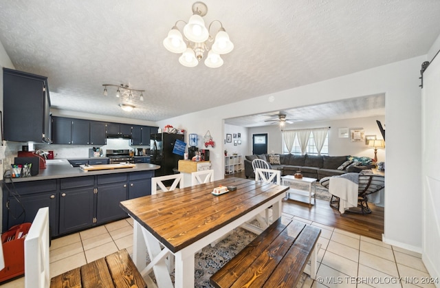 kitchen featuring light hardwood / wood-style floors, ceiling fan with notable chandelier, a textured ceiling, stainless steel range oven, and black fridge