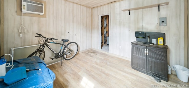 miscellaneous room featuring hardwood / wood-style flooring, wood walls, and an AC wall unit