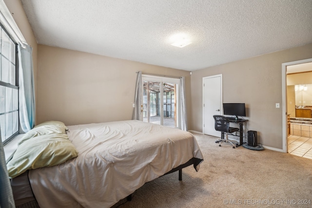 bedroom with a textured ceiling, light carpet, ensuite bath, and access to exterior