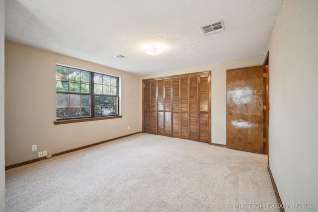 unfurnished bedroom featuring a textured ceiling, a closet, and carpet flooring