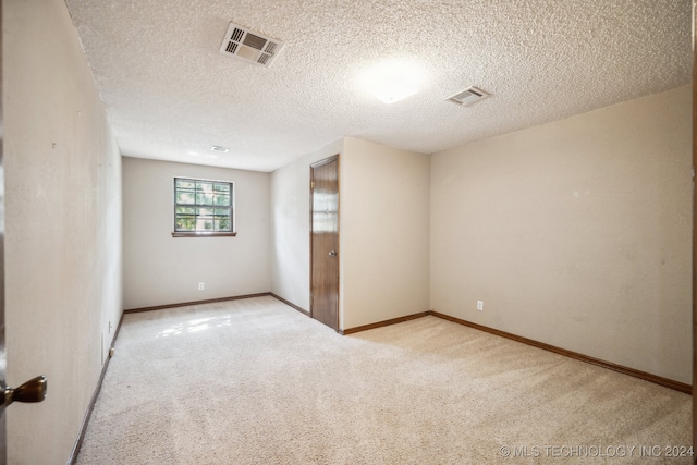 unfurnished room featuring light colored carpet and a textured ceiling