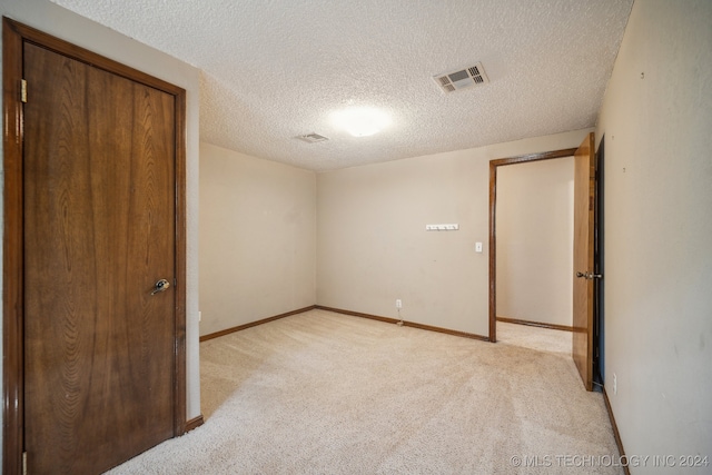 unfurnished bedroom featuring a textured ceiling, a closet, and light carpet