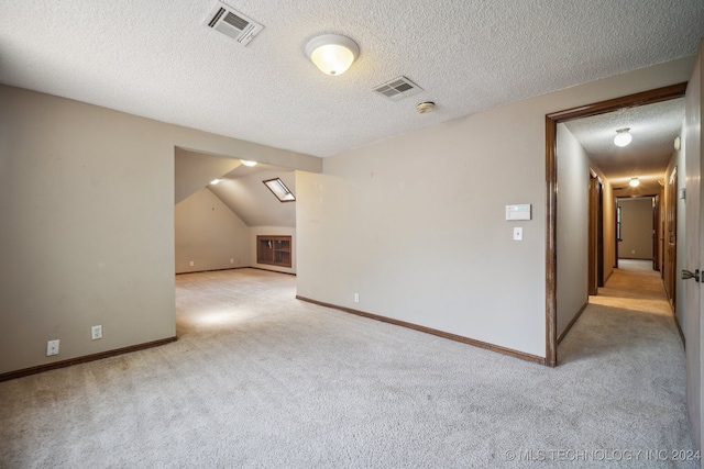 empty room with a textured ceiling, light carpet, and lofted ceiling