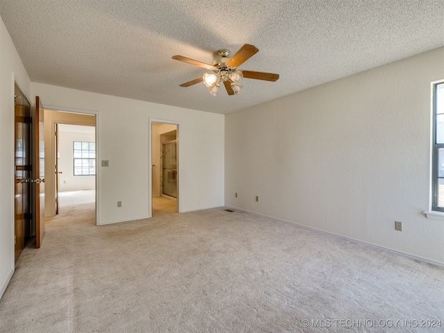 unfurnished bedroom featuring ceiling fan, a textured ceiling, and light colored carpet