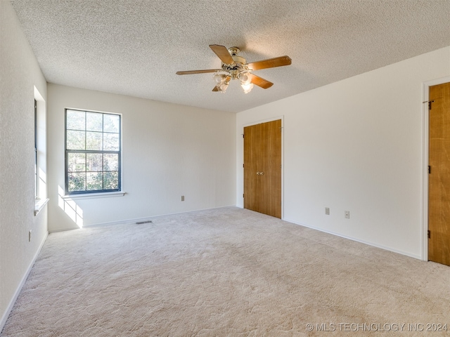 carpeted spare room featuring ceiling fan and a textured ceiling