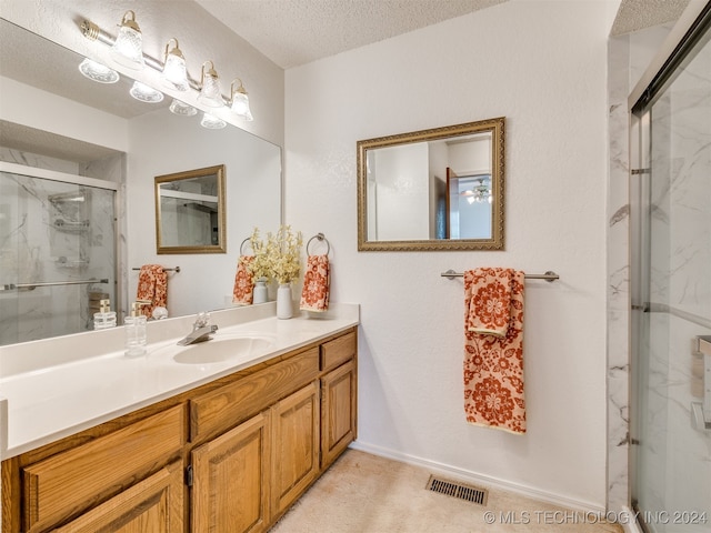 bathroom featuring vanity, a textured ceiling, and a shower with shower door