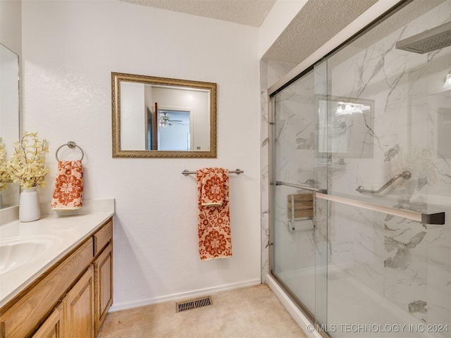 bathroom featuring a shower with door, vanity, and a textured ceiling