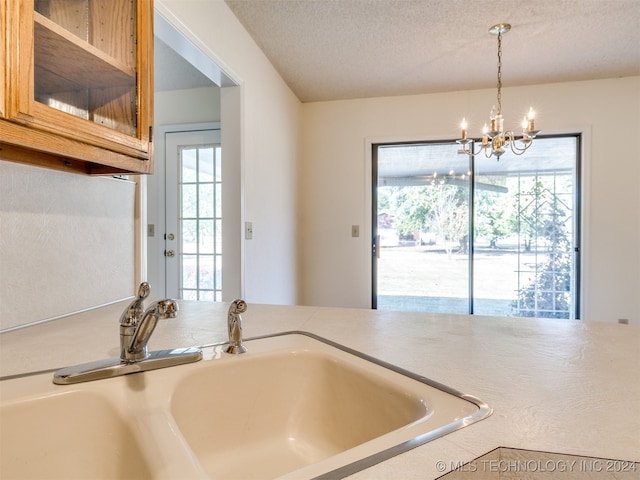 kitchen featuring a notable chandelier, a healthy amount of sunlight, a textured ceiling, and sink