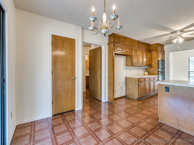 kitchen featuring oven, ceiling fan with notable chandelier, a textured ceiling, pendant lighting, and built in microwave