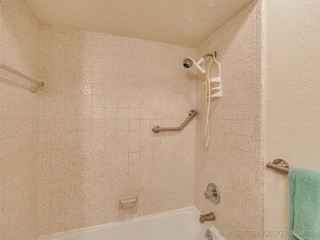 bathroom with tiled shower / bath and a textured ceiling