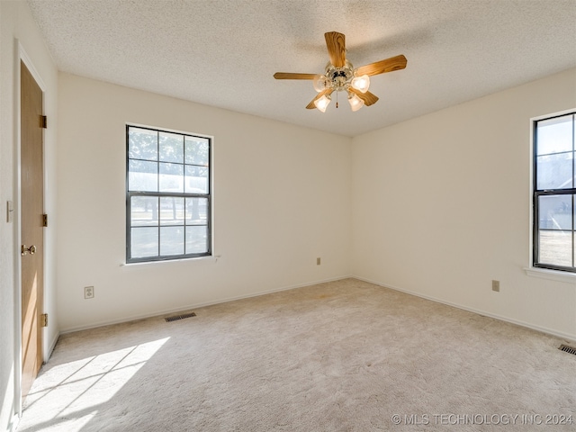 carpeted spare room featuring a textured ceiling and ceiling fan