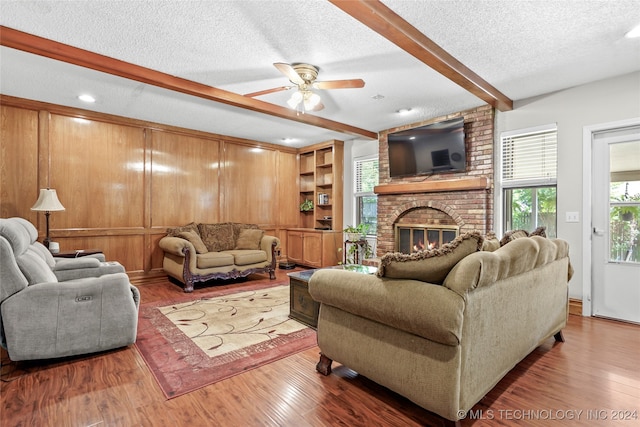 living room with beamed ceiling, hardwood / wood-style floors, a textured ceiling, and a fireplace