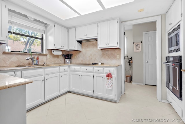 kitchen with decorative backsplash, sink, white cabinetry, and black appliances