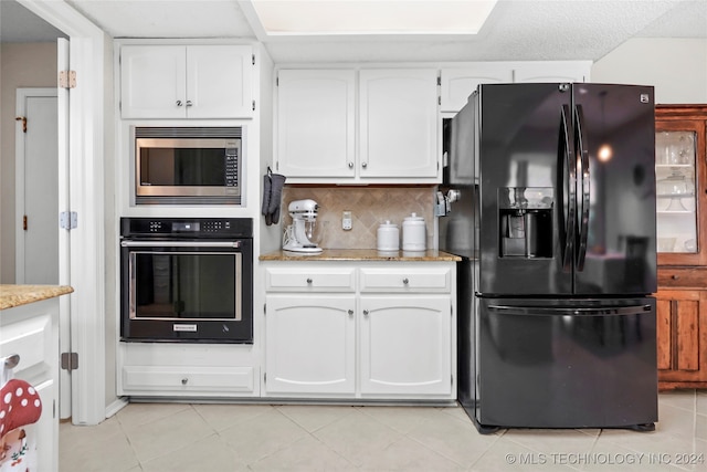 kitchen with decorative backsplash, light tile patterned flooring, white cabinetry, and black appliances