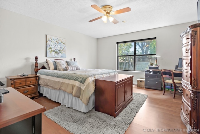 bedroom featuring ceiling fan, light hardwood / wood-style floors, and a textured ceiling