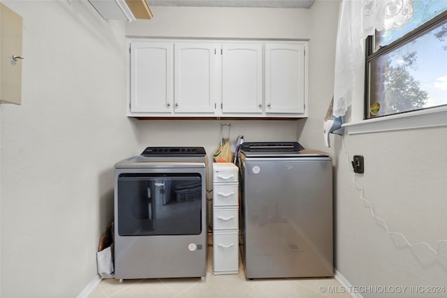 laundry area featuring cabinets, light tile patterned floors, and washing machine and clothes dryer