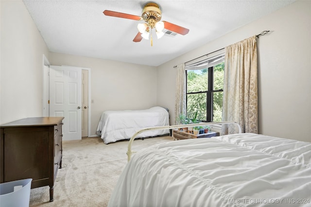 carpeted bedroom featuring ceiling fan and a textured ceiling