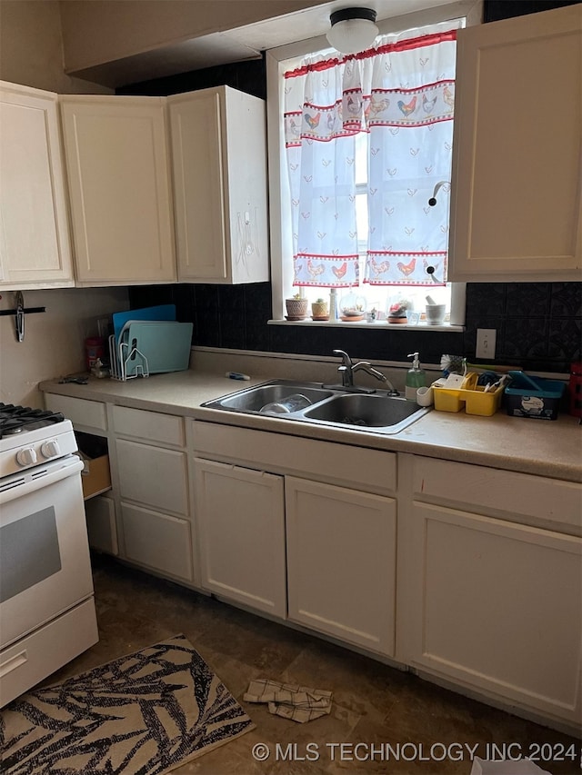 kitchen featuring backsplash, white cabinets, sink, and gas range gas stove