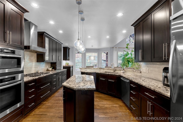 kitchen with sink, decorative light fixtures, wall chimney exhaust hood, dark wood-type flooring, and a center island